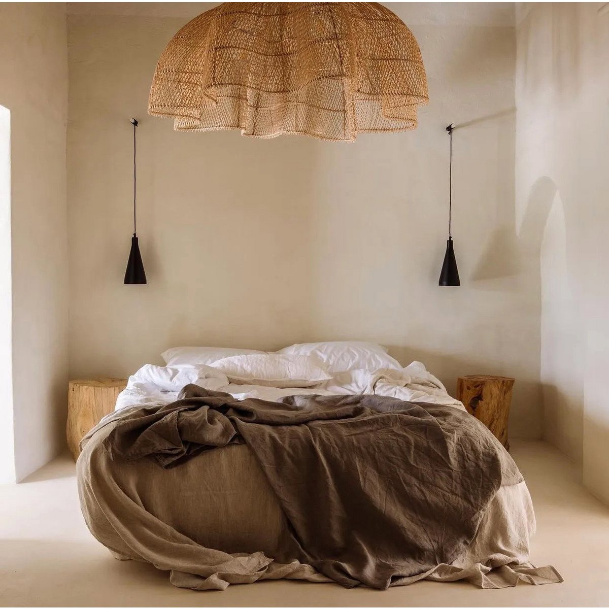 Suspension CÉLESTE XXL en rotin naturel dominant un lit dans une chambre épurée