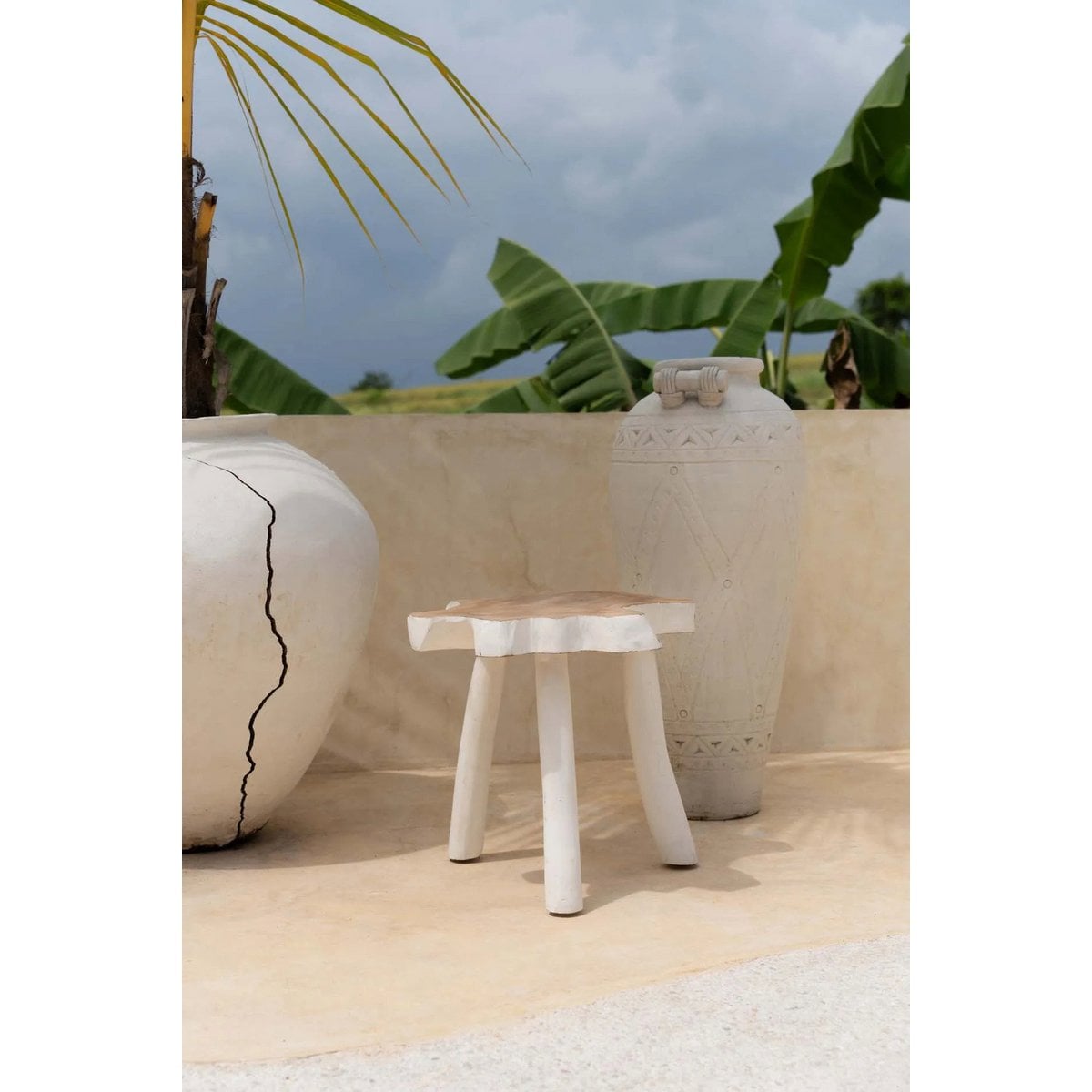 Table d’appoint LUNA blanc naturel dans un décor minéral avec végétation