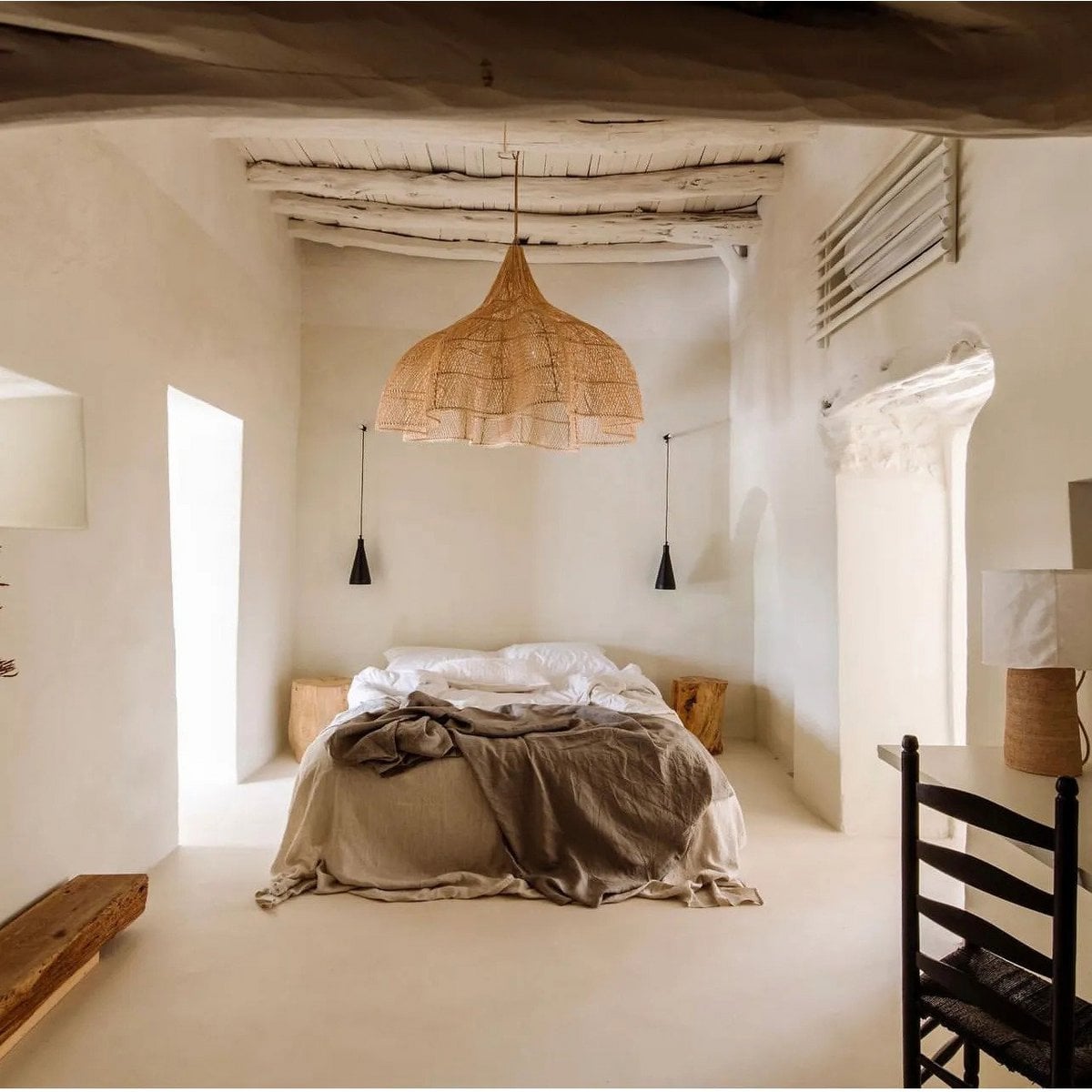 Suspension CÉLESTE XXL en rotin naturel au-dessus d’un lit dans une chambre claire